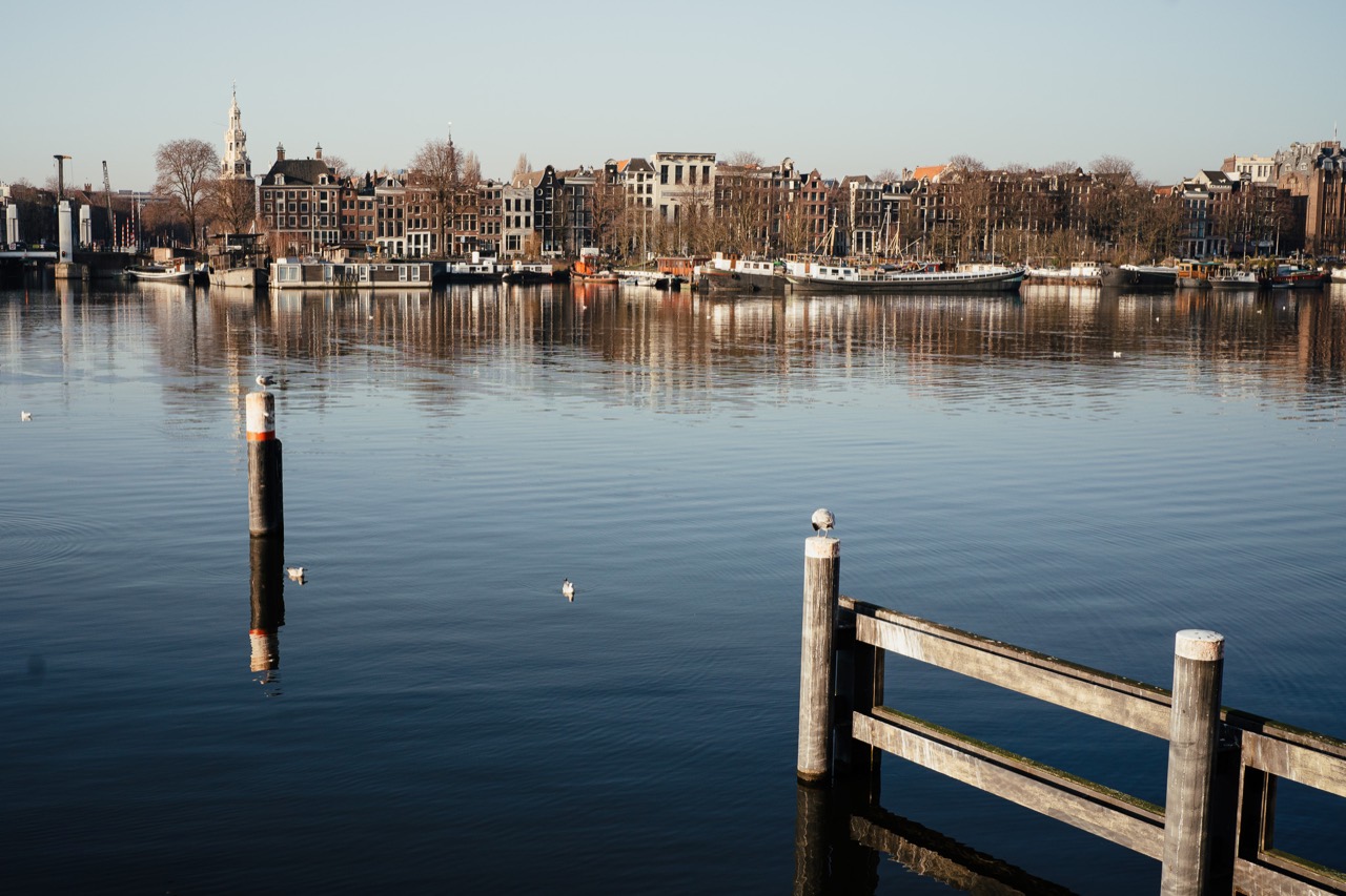 Waterfront buildings reflected in calm water beyond a wooden railing