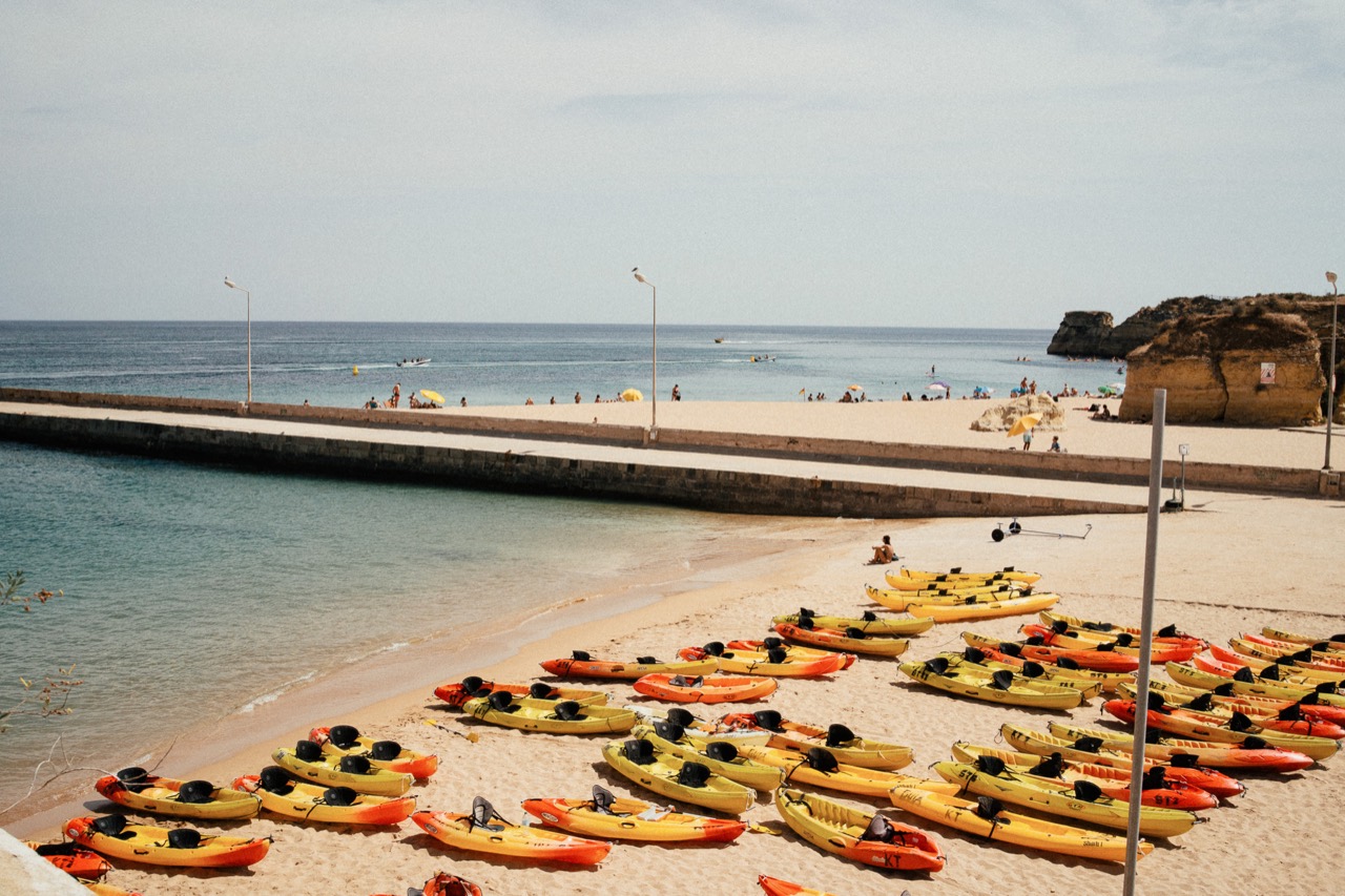 Brightly coloured kayaks lined up on a sandy beach