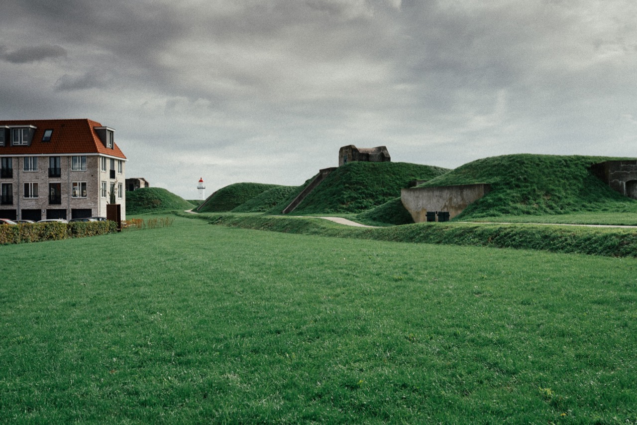 Grassy earthworks and old stone ruins beneath a cloudy sky