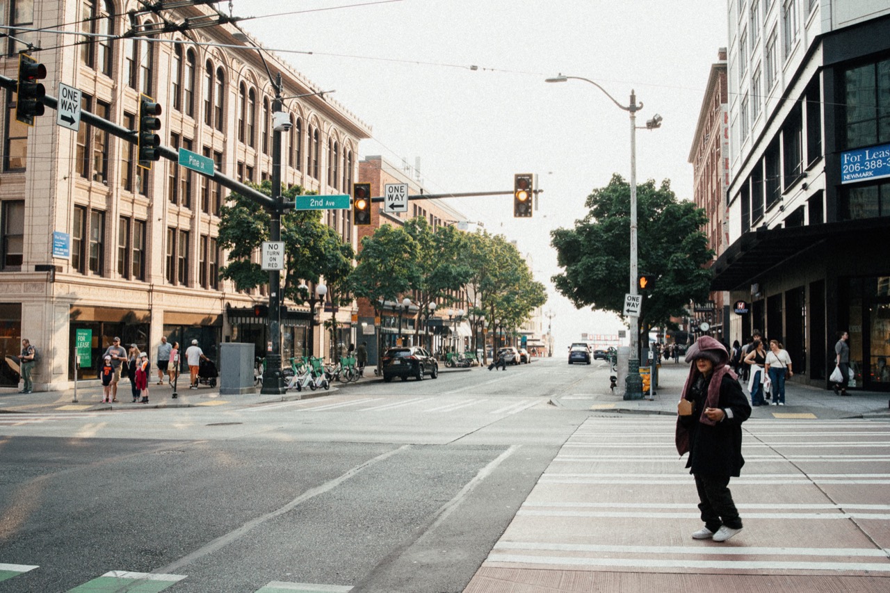 Pedestrians crossing a downtown street lined with tall buildings