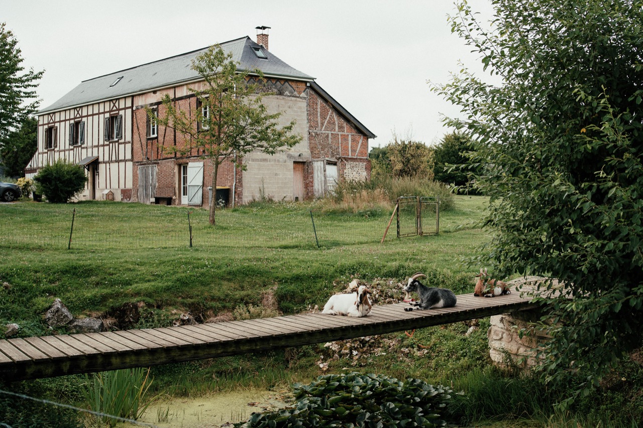 A brick farmhouse and green garden beside a narrow canal