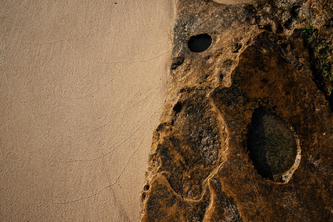 Warm light across a textured stone surface with dark rounded cavities