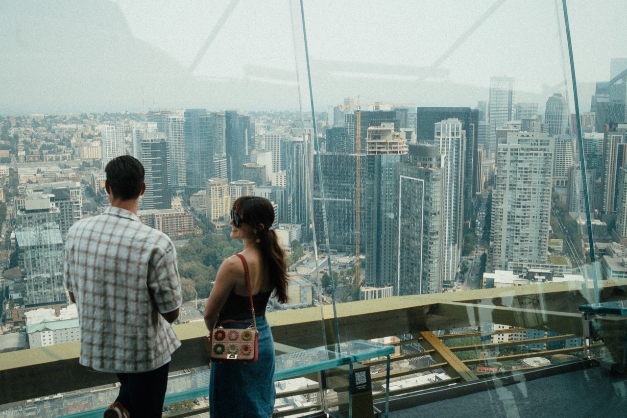 Two visitors looking across the city from a high observation deck