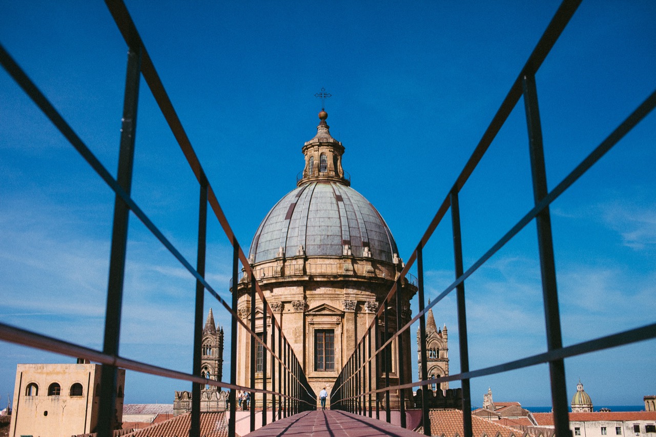 A stone dome framed by blue metal beams against a clear sky