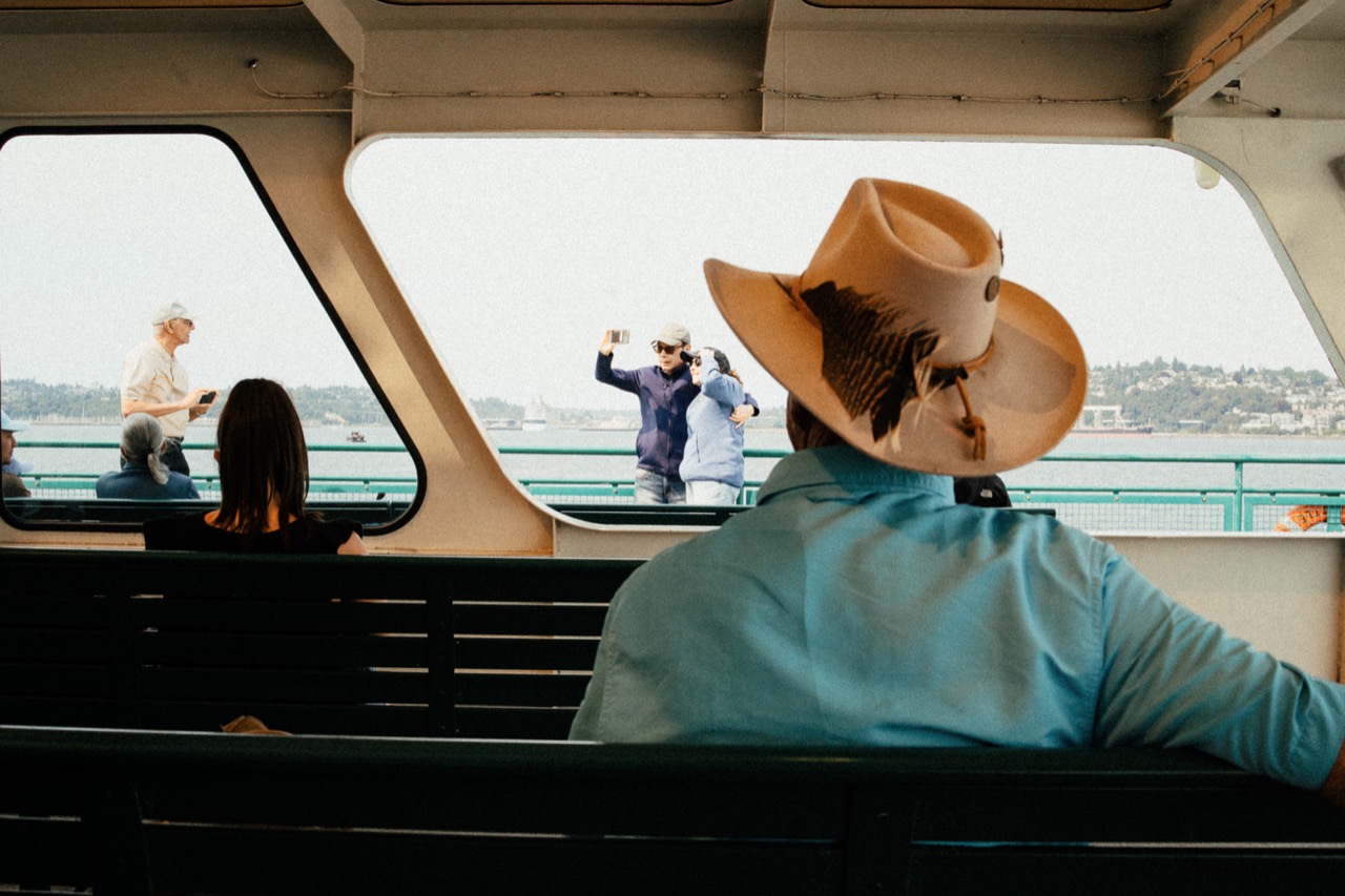 A passenger wearing a straw hat looking through a boat window