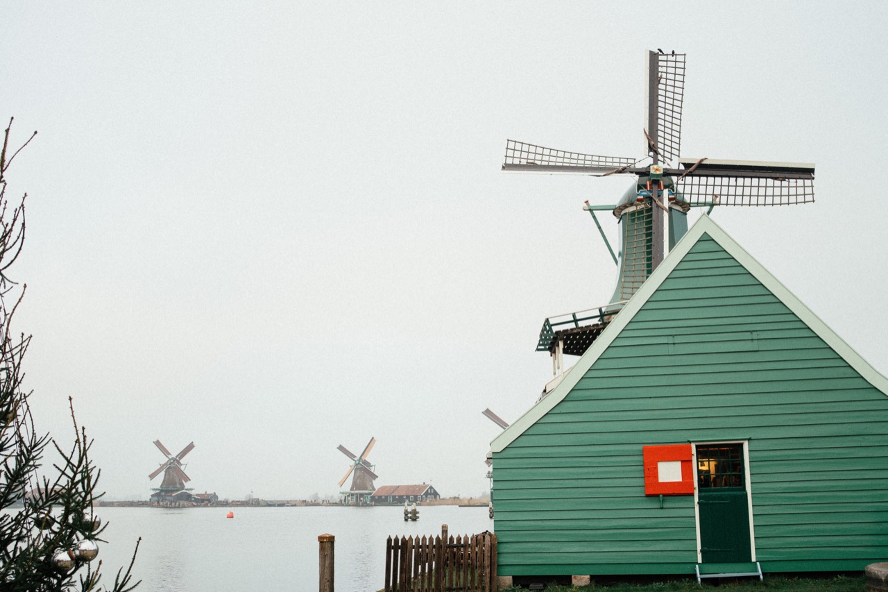 A green wooden building beneath the sails of a traditional windmill