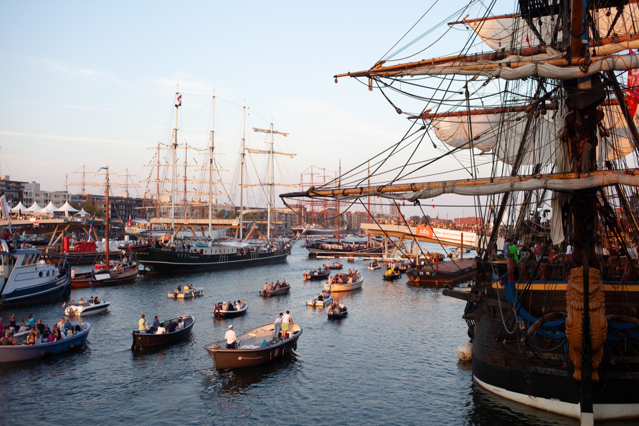 Sailing boats and tall ship rigging filling a sunlit harbour