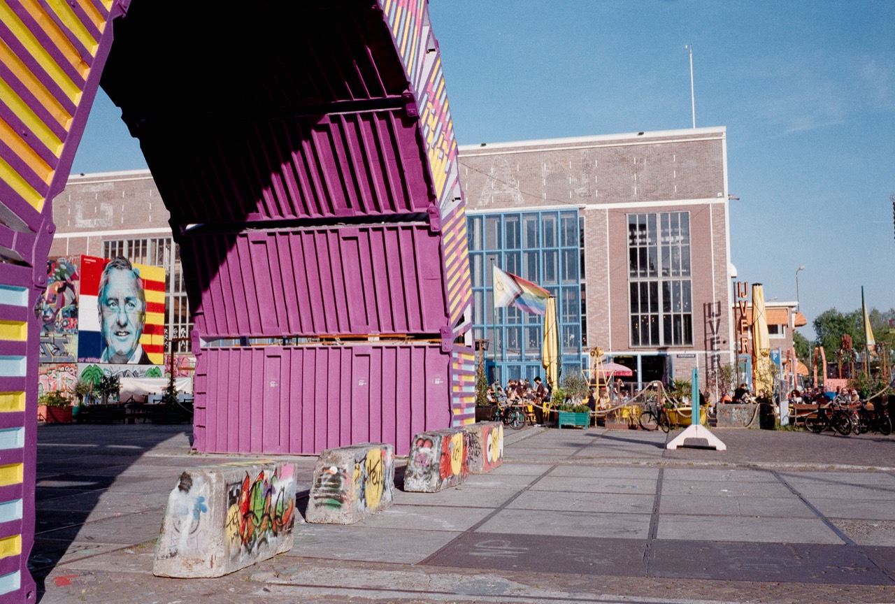 Bright purple shipping containers and colourful street art under a blue sky