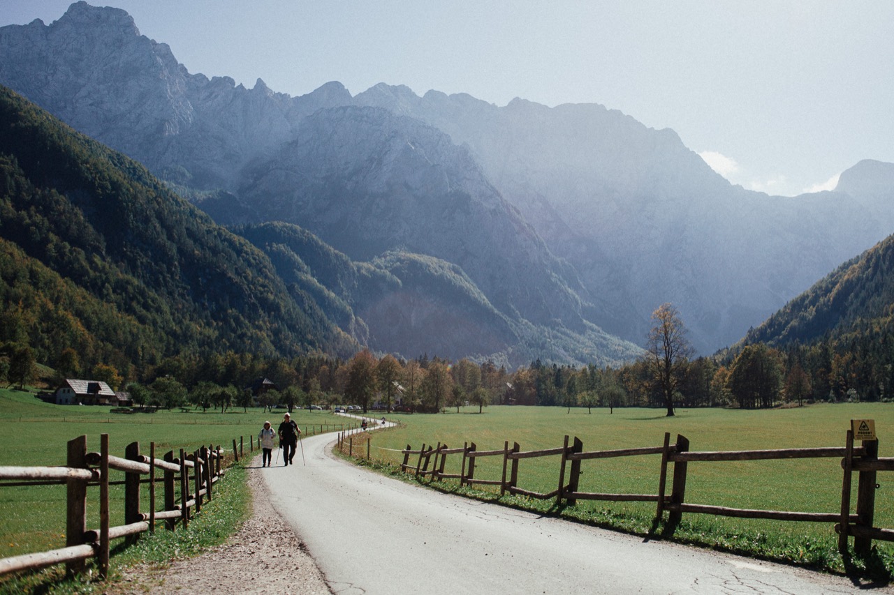 A winding path through green pasture beneath a dramatic mountain range